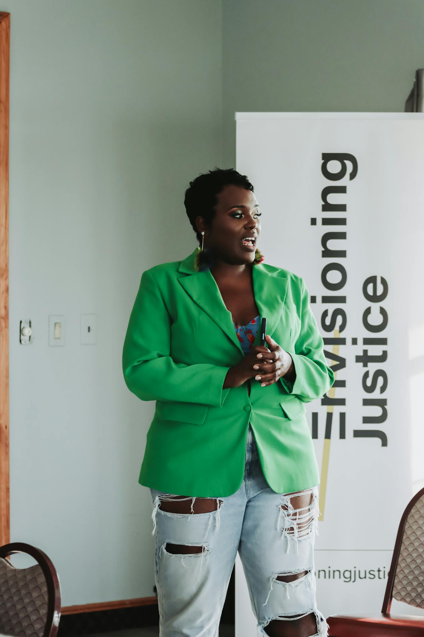 Confident woman in green blazer presenting at social justice event.